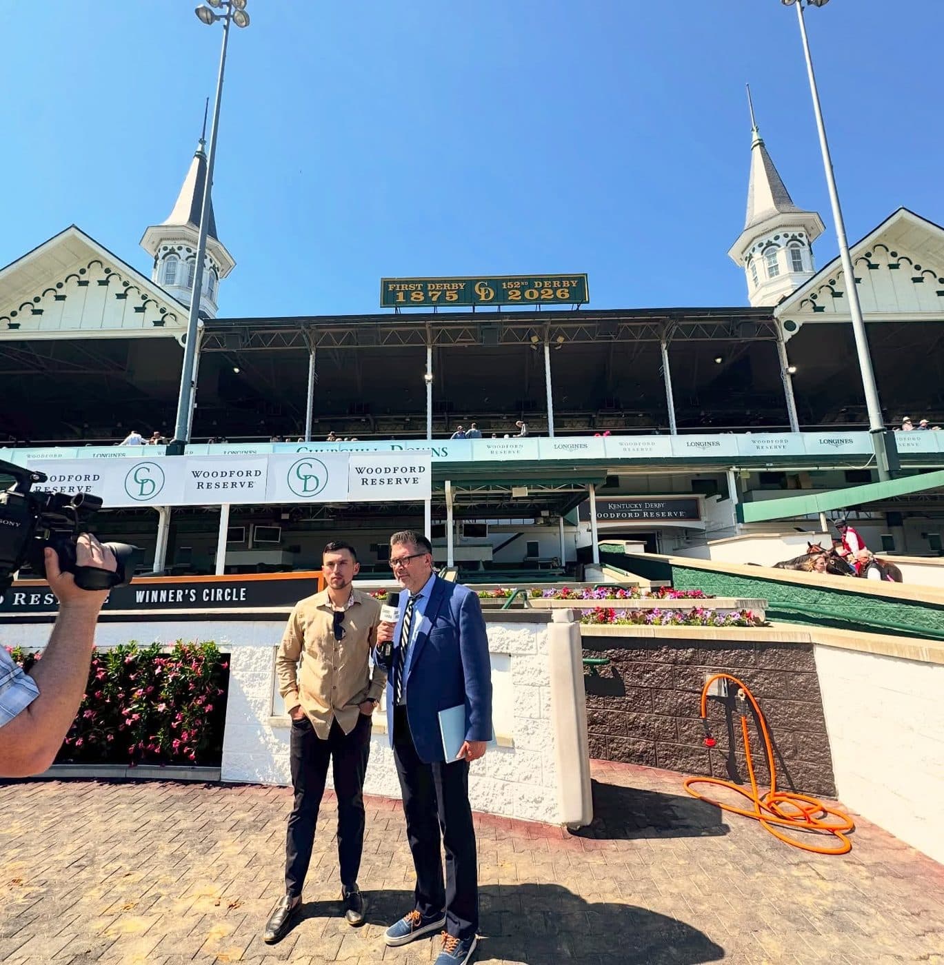 Nick Vaccarezza on camera at the Churchill Downs winner's circle, the twin spires behind him